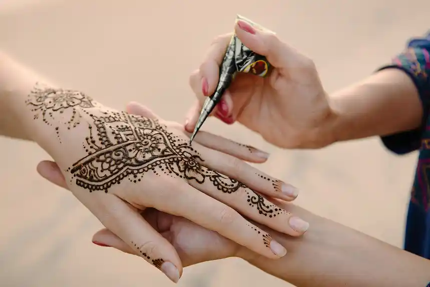 Artist applying henna tattoo on women
