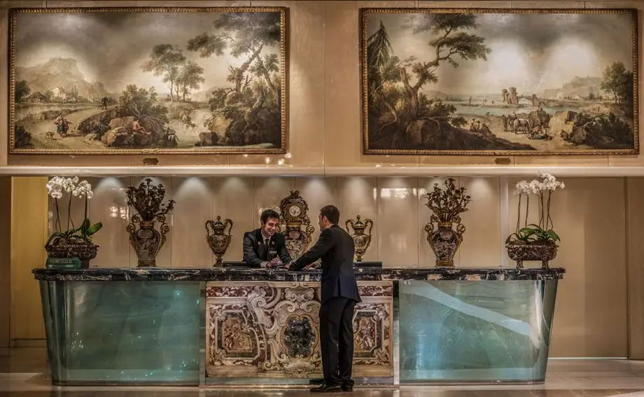 Rome Cavalieri Lobby Entrance concierge Desk with Zais Paintings - ALO Magazine